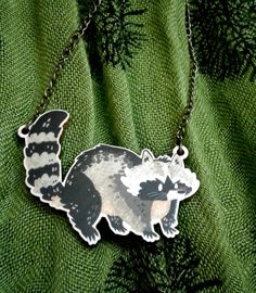 a raccoon necklace on a green background