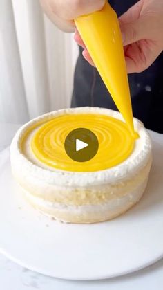 a person is decorating a cake with yellow icing