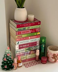 a stack of books sitting on top of a white shelf next to a potted plant