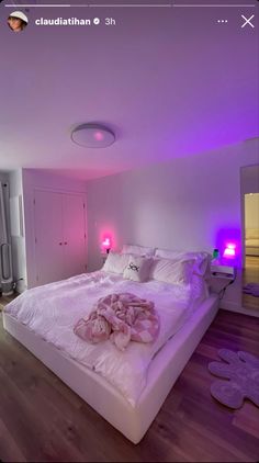 a large bed sitting inside of a bedroom next to a purple light