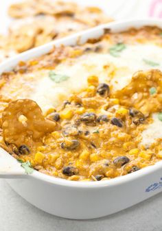 a casserole dish filled with cheese and black olives, topped with a tortilla chip