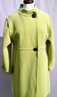 a woman's green coat is shown on a mannequin headdress