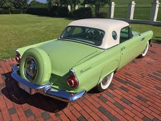 an old green and white car parked on brick walkway