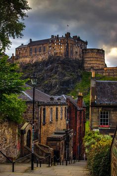 an old castle on top of a hill with stairs leading up to the building below