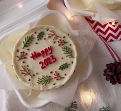 a decorated cake sitting on top of a white plate next to pine cones and christmas decorations