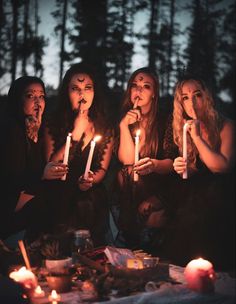 four women holding candles in front of their faces