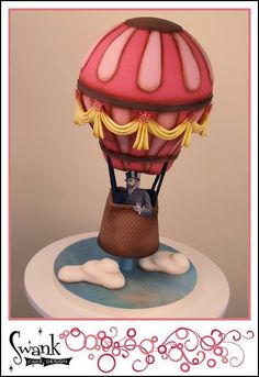 a cake with a hot air balloon on it's top and clouds around it