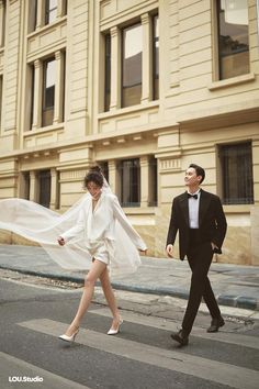 a man and woman in formal wear crossing the street