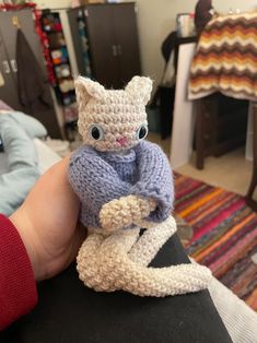 a hand holding a small knitted cat