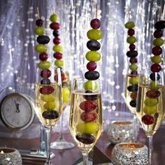 some glasses filled with different types of food on a table next to a clock and curtain