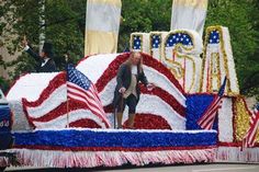 a man standing on the back of a float with american flags and stars in it