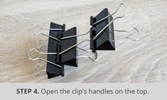 three pieces of black paper on top of a wooden table with text overlay that reads, step 4 open the clips handles on the top