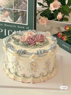 there is a cake on the table with flowers in front of it and a book behind it