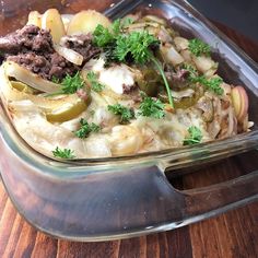 a casserole dish with meat and vegetables in it on a wooden table top