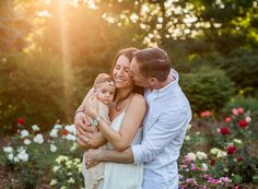 a man and woman hugging each other in front of some flowers with the sun shining on them