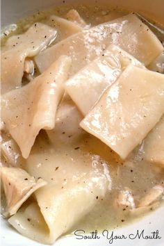 a white bowl filled with pasta and meat covered in gravy on top of a table