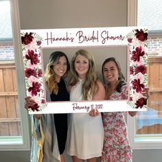 three women pose for a photo in front of a floral frame