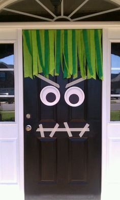 a black door decorated with green grass and eyes