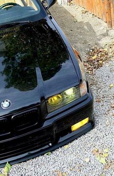 the front end of a black car parked on gravel