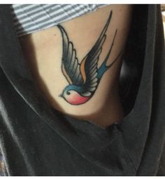 a small bird tattoo on the side of a woman's leg