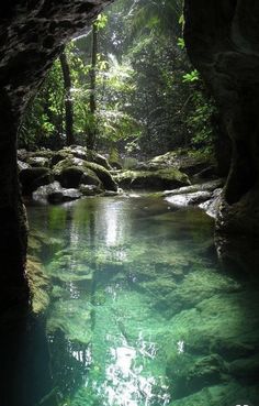 the water is crystal green and clear in this cave like area with mossy rocks on both sides