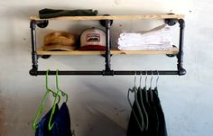 the hat rack is holding hats and other items on it's shelf, along with two pairs of pants