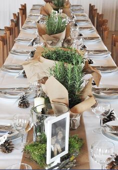 the table is set with pine cones and greenery