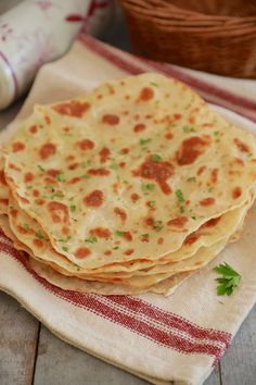 three flat breads are stacked on top of each other, with parsley in the background