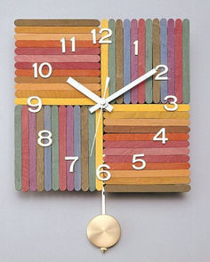 a clock made out of colored sticks with numbers on each side and a gold pendulum