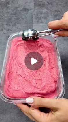 a person is holding a spoon over a bowl of pink ice cream with a video on it