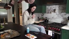 a woman sitting on top of a counter in a kitchen