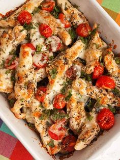 a casserole dish with chicken, tomatoes and herbs