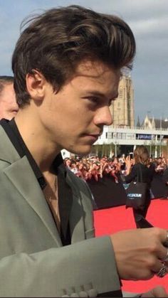 a man in a suit is looking at his cell phone while standing on the red carpet