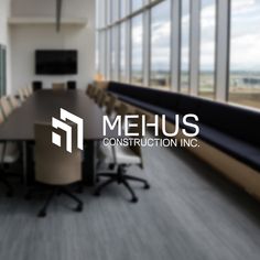 the mehus construction inc logo is shown in front of a conference room with large windows