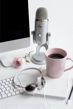 a cup of coffee and headphones sitting on a desk next to a computer keyboard