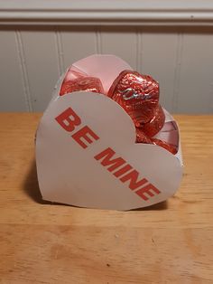 a heart shaped box filled with chocolates on top of a wooden table