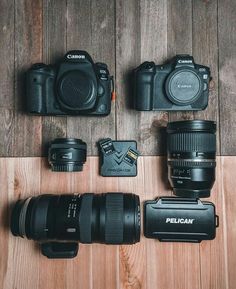 several cameras sitting on top of a wooden table next to each other with their lenses