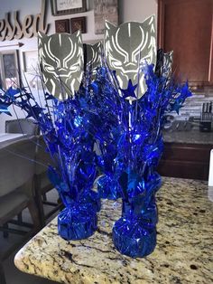 two blue vases sitting on top of a counter next to each other with decorative items in them