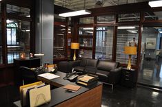 an office area with black leather couches and desks in the center, surrounded by wooden shuttered windows