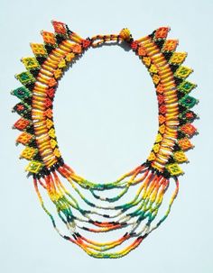 a multicolored beaded necklace is displayed on a white surface with a circular hole in the middle