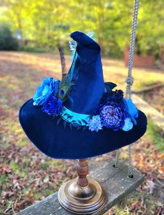 Welcome to the Bewitched Haberdashery!  This hat is made out of deep blue velvet with a 18 inch brim, has blue floral embellishments with peacock and roaster feathers and finished with crystal drops on the tip of the cone. It is filled and inner lined, so it won't lose shape.  Every hat I create is one-of-a-kind, so no one else will have one quite like it! Ready to ship immediately, and shipping usually takes 2-4 days for anywhere in the US! Adjustable Blue Costume Hats And Headpieces, Blue Hat For Kentucky Derby, Blue Hat For Kentucky Derby Festival, Whimsical Blue Wide Brim Hat, Whimsical Blue Wide-brim Hat, Blue Halloween Costume Hats And Headpieces, Blue Whimsical Costume Hats And Headpieces, Whimsical Blue Costume Hats And Headpieces For Festival, Handmade Adjustable Blue Costume Hats And Headpieces