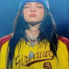 a woman with long black hair wearing a yellow shirt and blue hat is looking up at the sky