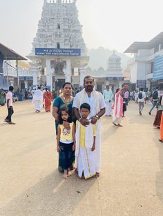 a man and two children standing in front of a temple