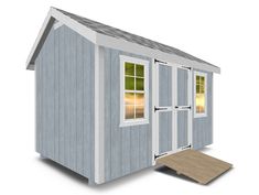 a small blue and white shed sitting on top of a wooden floor next to a ramp