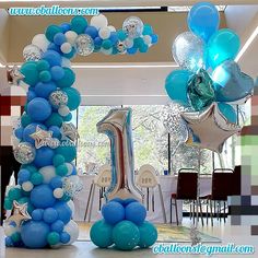 blue and white balloons are arranged in the shape of an arch for a first birthday party