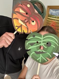 two people with masks on their faces posing for the camera, one is holding a stick