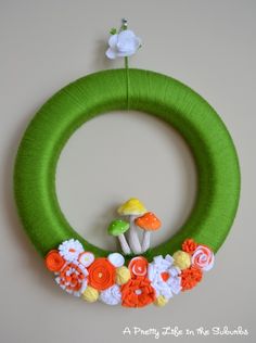 a green wreath with flowers and mushrooms on it