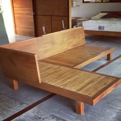 a wooden bench sitting on top of a cement floor next to a bed in a room