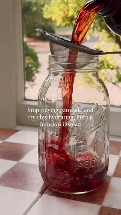 a person pouring red liquid into a glass jar on a checkered counter top with a quote written below