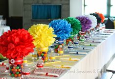 there are many colorful flowers in vases on the table with candy balls and pens